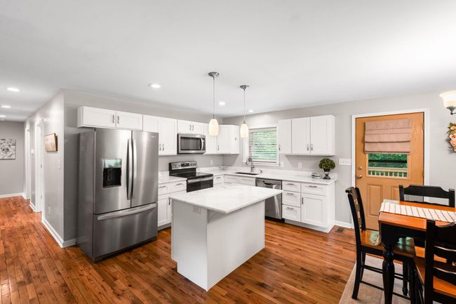 The updated kitchen has granite counters, stainless steep appliances, and a large island. | Image 11