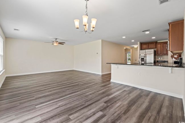 Kitchen featuring dark countertops, a chandelier, open floor plan, ceiling fan, and dark wood-type flooring | Image 20