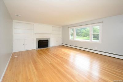 Unfurnished living room featuring light hardwood / wood-style flooring and baseboard heating | Image 3