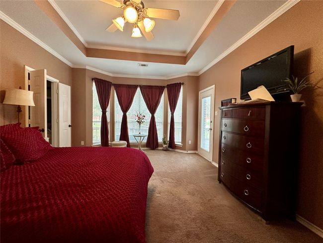 Carpeted bedroom with visible vents, crown molding, and a raised ceiling | Image 15