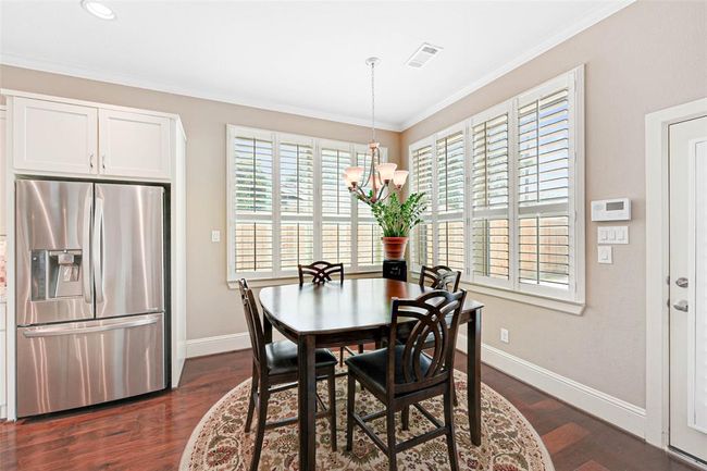 Charming breakfast nook with wraparound plantation shutters, wood floors, and a central chandelier. | Image 17