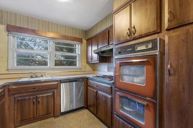 Kitchen featuring under cabinet range hood, a sink, brown cabinets, and appliances with stainless steel finishes | Image 10