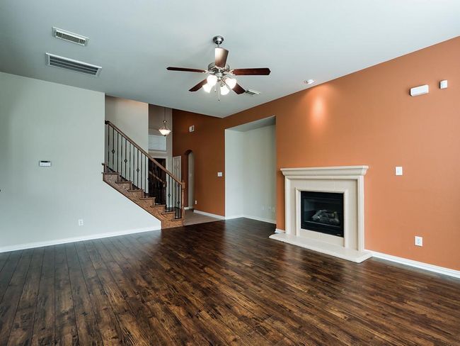 Unfurnished living room featuring ceiling fan, wood finished floors, and stairs | Image 22