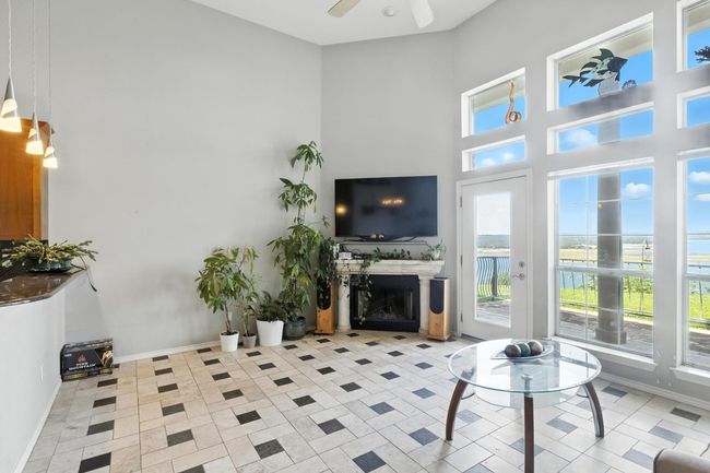Living area featuring a towering ceiling, a ceiling fan, and a fireplace | Image 11