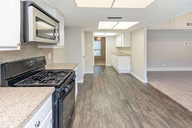 Kitchen featuring white cabinetry, tasteful backsplash, stainless steel microwave, black gas stove, and visible vents | Image 10