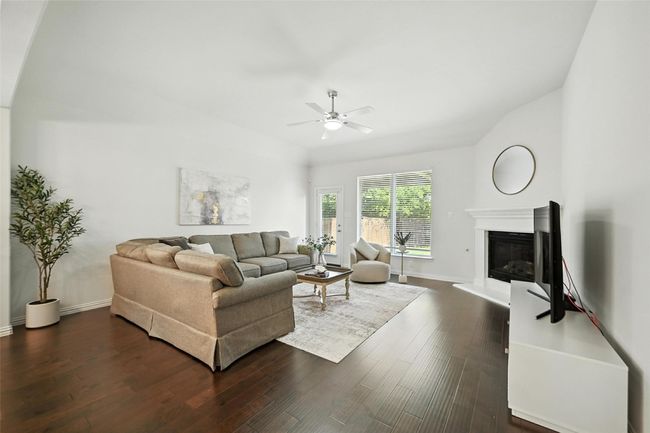 Living room with a glass covered fireplace, dark wood-style floors, and ceiling fan | Image 13