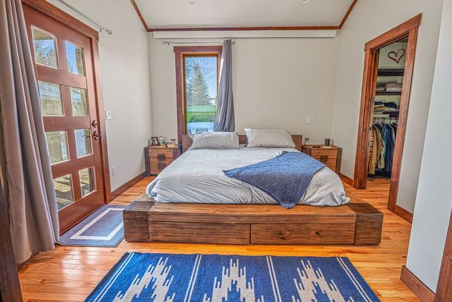 Bedroom with baseboards, wood finished floors, access to exterior, a walk in closet, and crown molding | Image 29