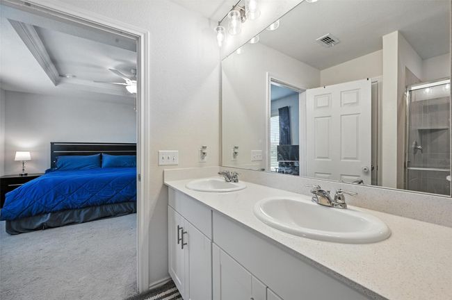 Ensuite bathroom featuring double vanity, a shower with door, and ceiling fan | Image 26