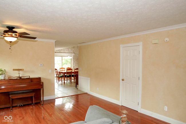 living room with a ceiling fan, wood finished floors, and crown molding | Image 6