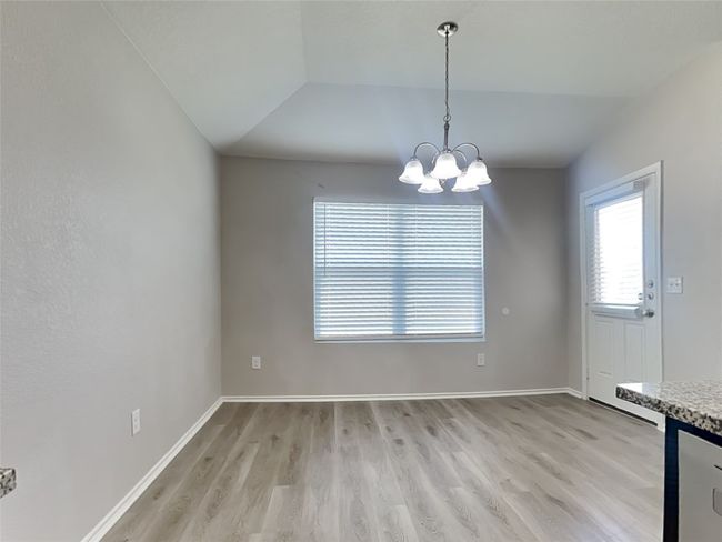 Unfurnished dining area with vaulted ceiling, light wood-style flooring, and a chandelier | Image 5