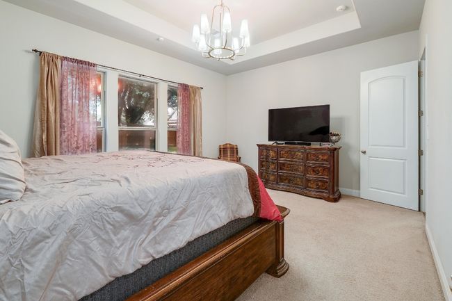 Bedroom with a raised ceiling, carpet, and a chandelier | Image 18