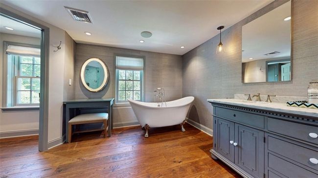 Bathroom featuring a bathtub, vanity with extensive cabinet space, and hardwood / wood-style floors | Image 24