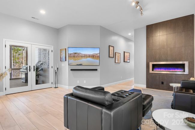 Modern style family room with custom ethanol fireplace and surround. French doors lead to covered and screened in deck space. | Image 13