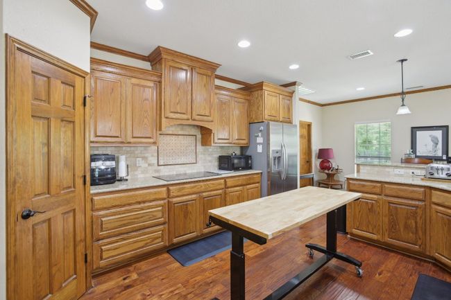 Kitchen featuring crown molding, dark wood-style floors, visible vents, black appliances, and decorative backsplash | Image 4