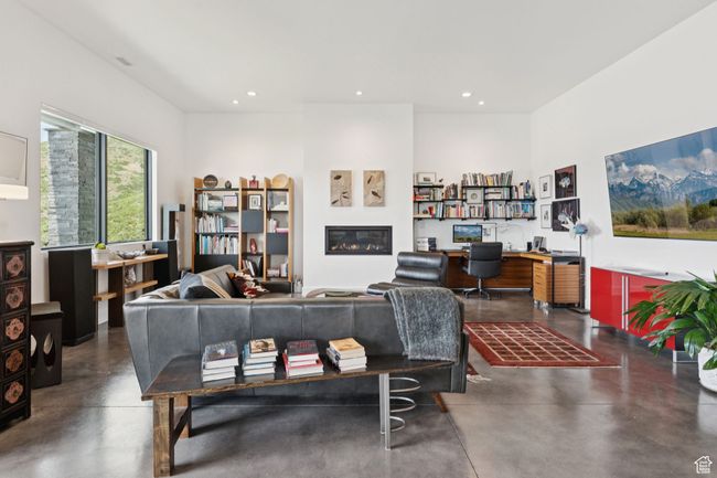 Living room with finished concrete floors, recessed lighting, a glass covered fireplace, and built in desk | Image 55
