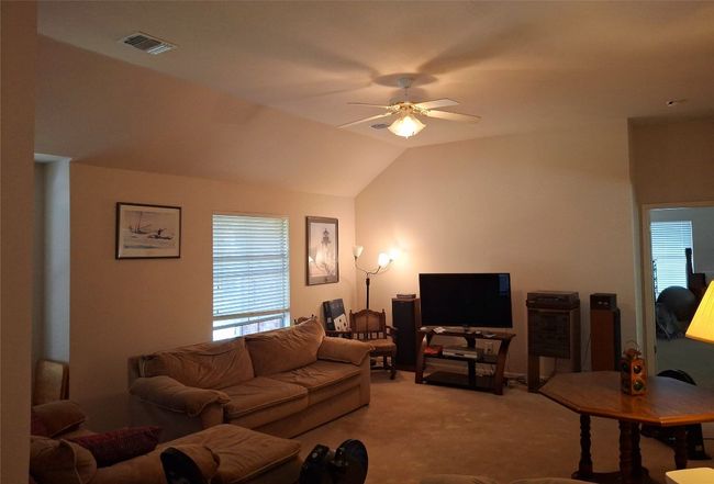 Living room featuring carpet floors, visible vents, vaulted ceiling, and a ceiling fan | Image 14