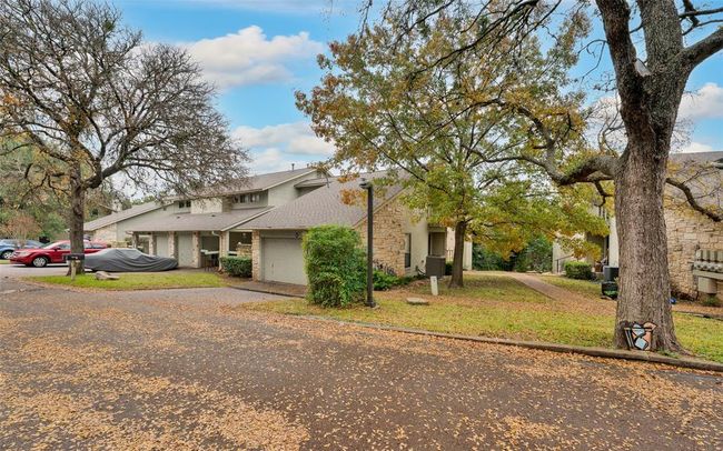 View of side of property featuring driveway, a garage, a yard, roof with shingles, and stone siding | Image 14