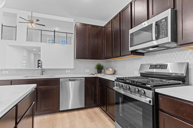 Close-up of the chef-style kitchen showcasing Quartz countertops, built-in microwave, gas range, and 42" upper cabinets that offer both storage and sleek style. **Image Representative of Plan Only and May Vary as Built**. | Image 14