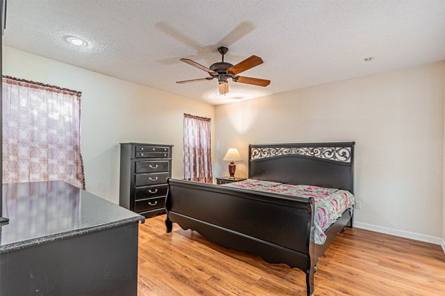 Bedroom with light wood finished floors, ceiling fan, and a textured ceiling | Image 16