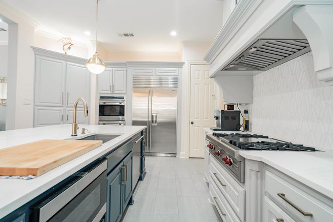 Kitchen with light countertops, appliances with stainless steel finishes, a sink, and custom range hood | Image 9