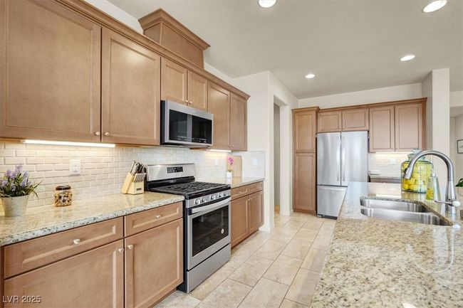 Kitchen featuring stainless steel appliances, light stone counters, backsplash, and recessed lighting | Image 18