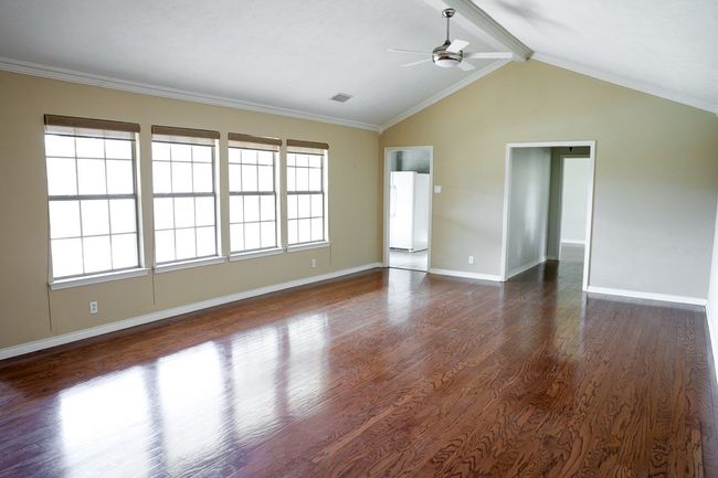 Empty room with ceiling fan and dark wood-style floors | Image 6