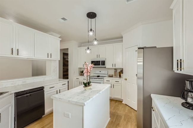 Kitchen featuring white appliances, white cabinets, light wood finished floors, pendant lighting, and ornamental molding | Image 8