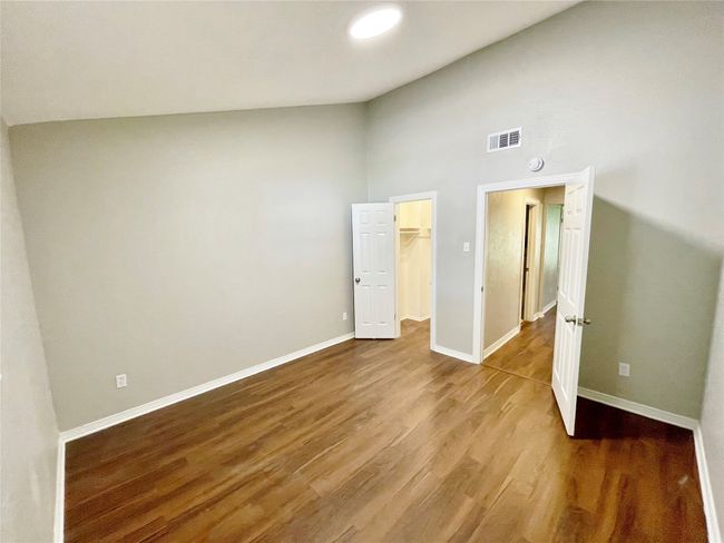 Unfurnished bedroom with high vaulted ceiling, wood finished floors, visible vents, and baseboards | Image 22