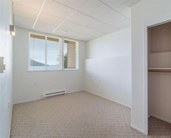 Unfurnished bedroom featuring baseboard heating, carpet, a drop ceiling, and baseboards | Image 50