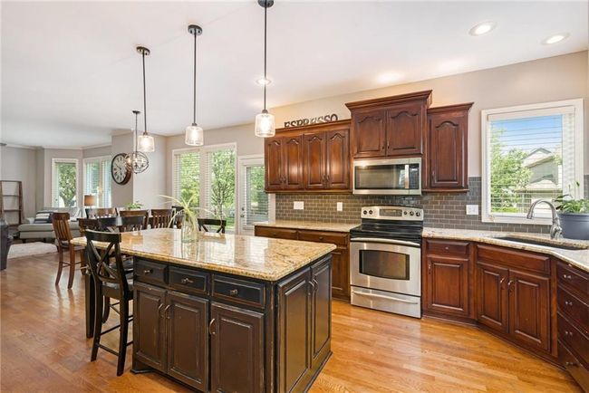 Kitchen featuring appliances with stainless steel finishes, a sink, light wood-type flooring, decorative backsplash, and pendant lighting | Image 14