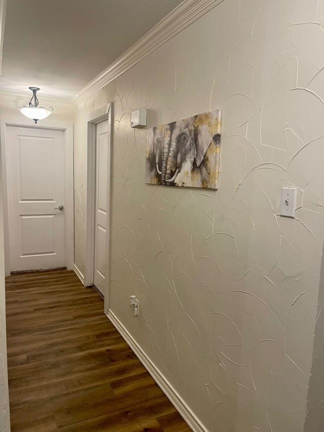 Hallway with wood finished floors, crown molding, and baseboards | Image 10