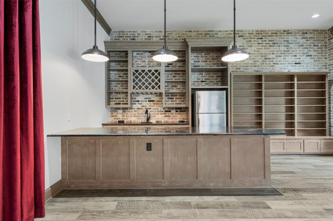 Bar with freestanding refrigerator, brick wall, pendant lighting, and light wood-type flooring. | Image 29