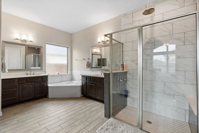 The ensuite bathroom features separate vanities, a soaking tub, and a walk-in shower, offering a perfect balance of functionality and relaxation | Image 17