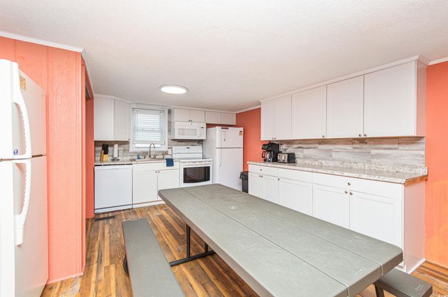 Kitchen with white appliances, light wood-style flooring, decorative backsplash, light countertops, and ornamental molding | Image 13