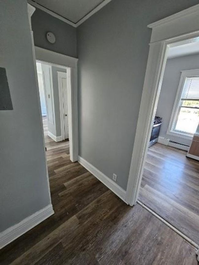 Hall featuring ornamental molding, dark wood-type flooring, baseboards, and baseboard heating | Image 5