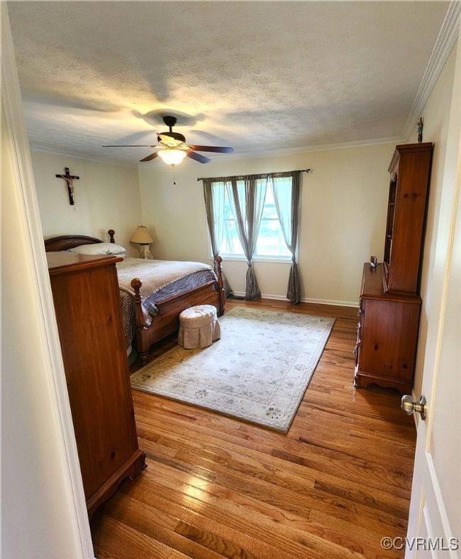 Bedroom with wood finished floors, a textured ceiling, ceiling fan, and ornamental molding | Image 13