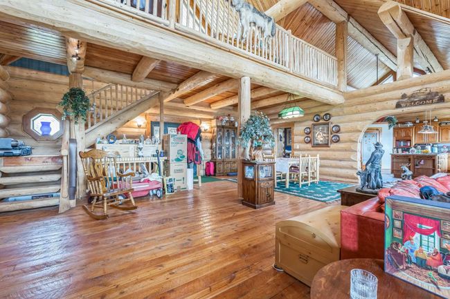 Living area featuring log walls, hardwood / wood-style flooring, wooden ceiling with exposed beams, stairway, and arched walkways | Image 27
