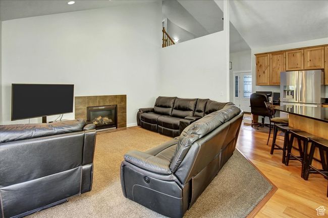 Living room featuring high vaulted ceiling, recessed lighting, a tile fireplace, and light wood-style flooring | Image 7