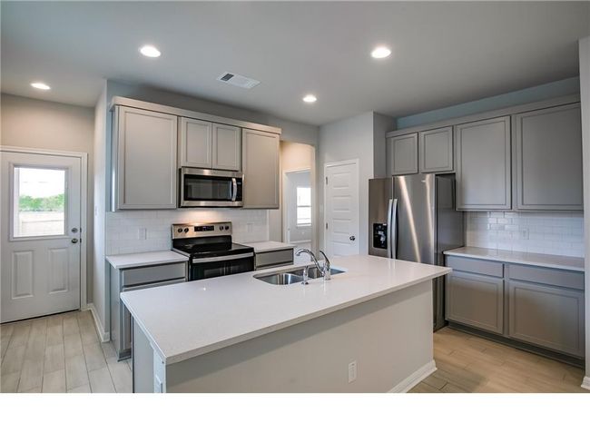 Kitchen featuring appliances with stainless steel finishes, gray cabinets, healthy amount of natural light, decorative backsplash, and recessed lighting | Image 9