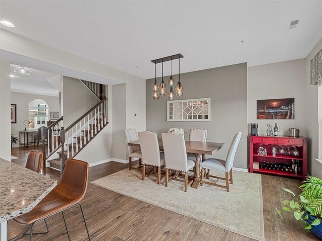 This elegant dining area offers a warm and inviting atmosphere, featuring a large table with seating for eight, a contemporary light fixture, and a soft area rug that defines the space. | Image 9