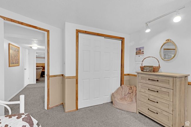 Bedroom featuring light colored carpet, rail lighting, and a closet | Image 31