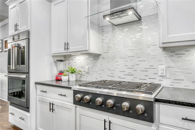 Kitchen with decorative backsplash, stainless steel appliances, and white cabinets | Image 17