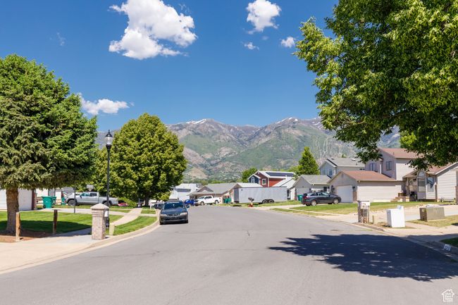View of asphalt street featuring sidewalks, a residential view, curbs, street lighting, and a mountain view | Image 27