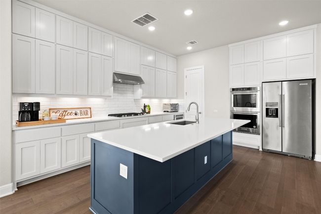 Kitchen with stainless steel appliances, dark wood finished floors, backsplash, extractor fan, and light countertops | Image 17