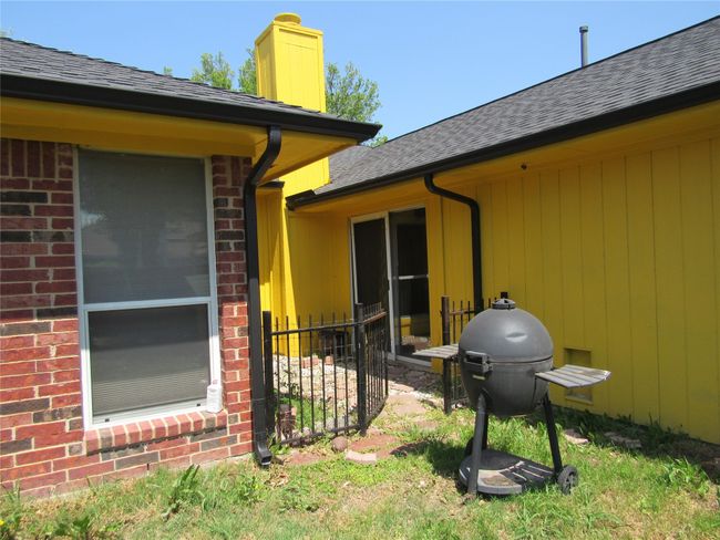 View of property exterior featuring brick siding, a shingled roof, a chimney, and fence | Image 26