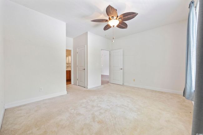 Unfurnished bedroom featuring light colored carpet, baseboards, and ceiling fan | Image 9