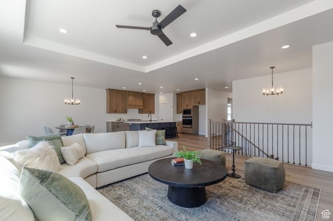 Living room featuring a chandelier, ceiling fan, light wood-style flooring, recessed lighting, and a tray ceiling | Image 10