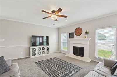 Living room featuring light colored carpet, ornamental molding, and ceiling fan | Image 2