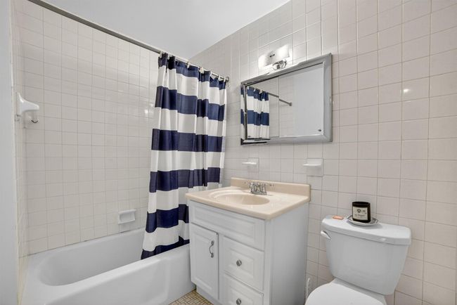 Bathroom featuring tile walls, vanity, shower / bath combination with curtain, and decorative backsplash | Image 25