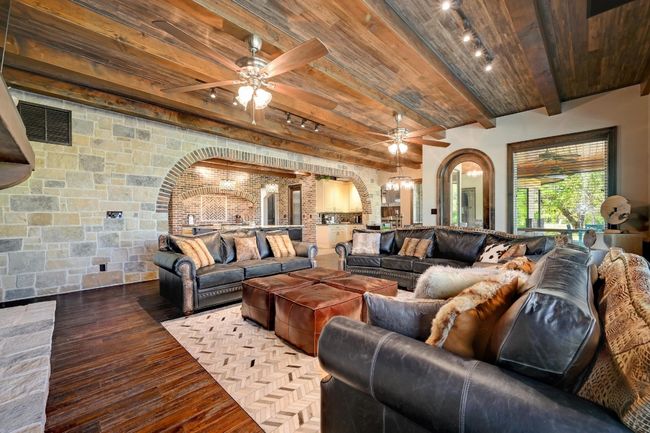 Living room with arched walkways, wooden ceiling, beam ceiling, and ceiling fan | Image 12